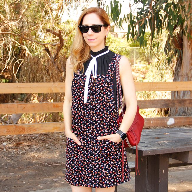 Southern California fashion blogger The Key To Chic wears a Who What Wear tie neck blouse with a floral overall dress and Rebecca Minkoff Swing bag.